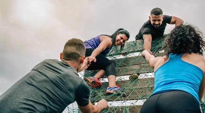 people helping people up an obstacle course