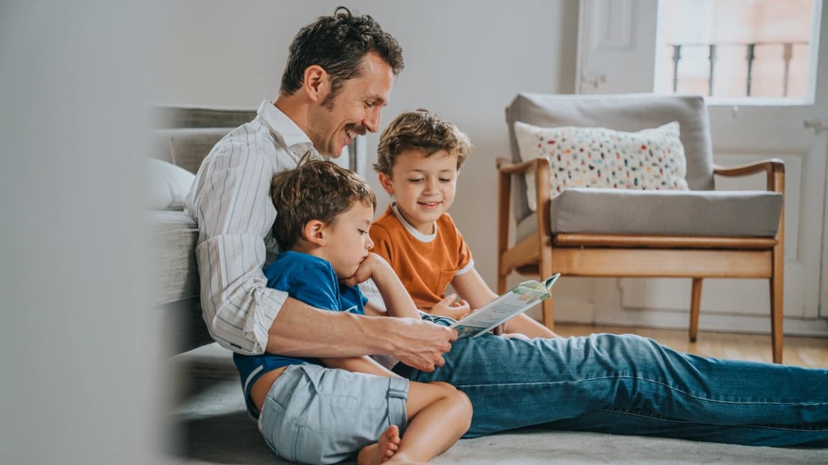 Dad reading a book to his two children who sit beside him. 