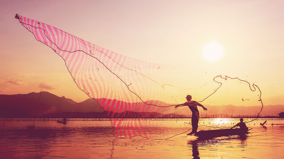 hombre lanzando una gran red de pesca al atardecer