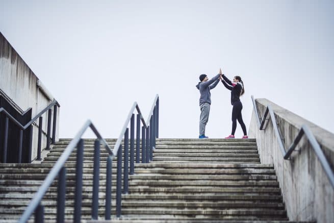 two runners high-fiving at the top of stairs