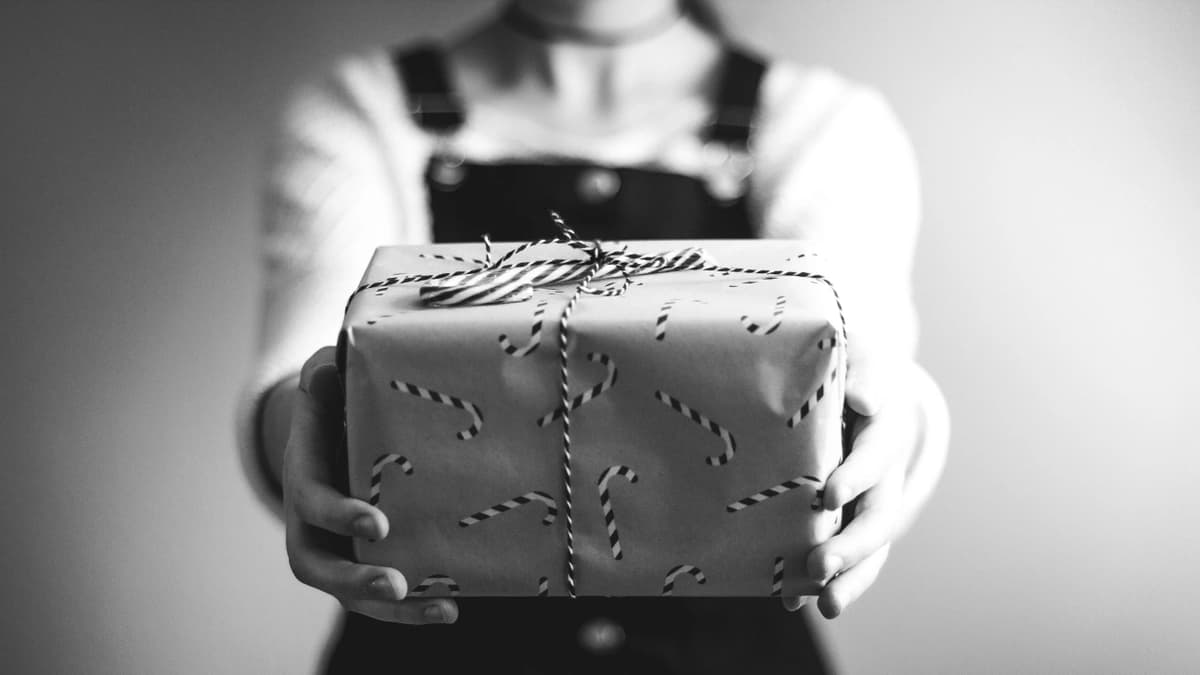 woman holding out present wrapped with candy cane wrapping paper