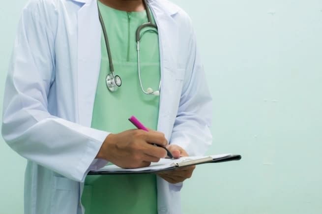 torso of a doctor writing on clipboard